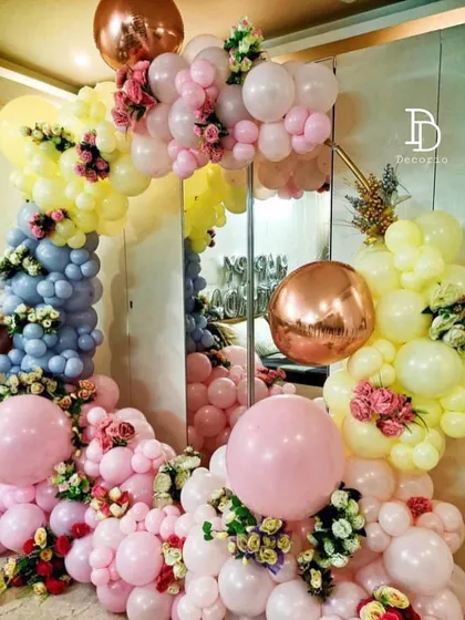 A beautiful ring decoration with a mix of pastel yellow, pink, and blue balloons, accented with fresh flowers. This setup is perfect for birthdays, anniversaries, or bridal showers.