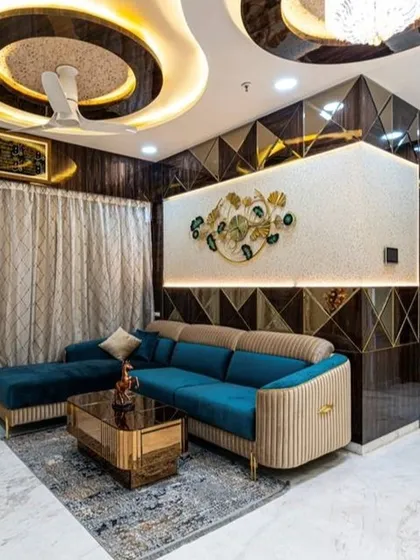 This living room in Jogeshwari is the epitome of modern luxury. We designed a complex, multi-layered ceiling with cove lighting to create drama and warmth. The combination of a plush teal sofa, reflective geometric wall panels, and bespoke furniture creates a space that is both glamorous and inviting, perfect for entertaining or relaxing.