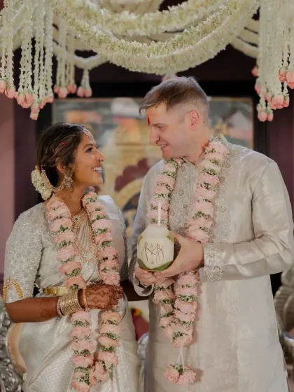 The couple shares a coconut, and the bride's rich henna stain is a beautiful detail in this happy moment.
