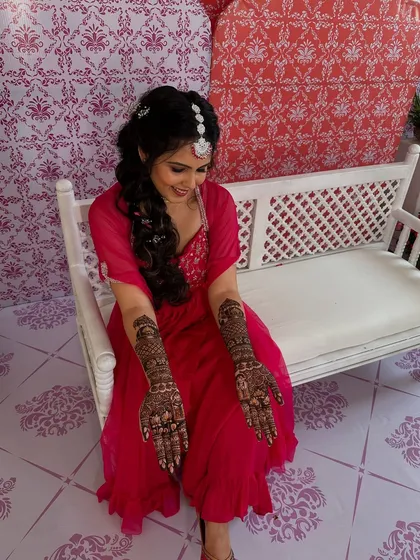 A happy client displaying her full-coverage traditional mehndi, the rich design extending all the way up her forearms.