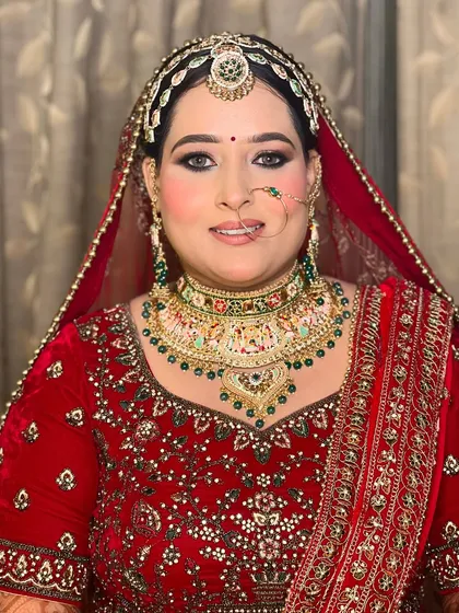 A classic portrait of a bride in a red lehenga, her makeup is bold and defined, with smokey eyes and a radiant base.