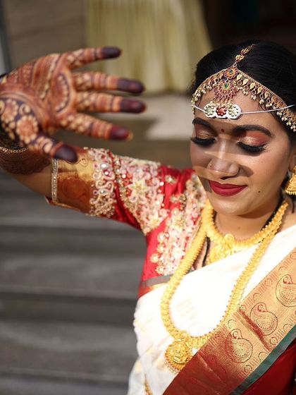 A beautiful shot of a bride in a traditional white and red saree, her dark mehendi stain adding to the classic look.