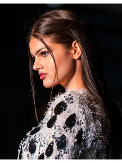 A profile shot of a model on the runway, highlighting her features and the intricate details of her sequined outfit. These candid-style ramp shots are perfect for capturing the natural grace of the models during the show.