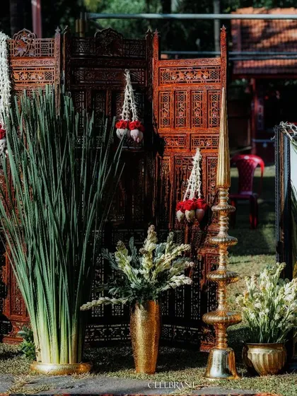 A warm, traditional welcome for wedding guests. This setup combines carved wooden screens, brass lamps, and fresh jasmine garlands to create an authentic and inviting entrance.