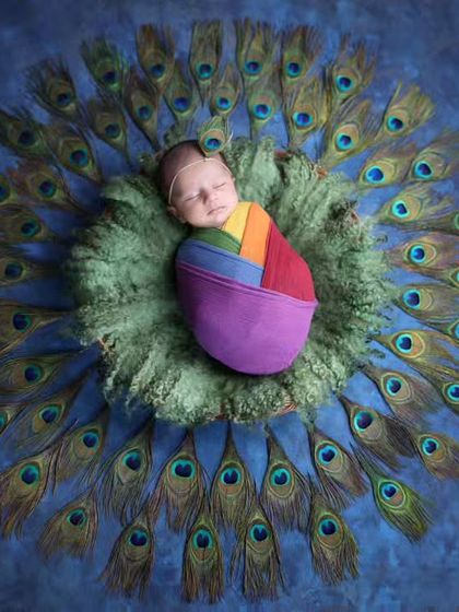 A stunning portrait inspired by Lord Krishna, with the newborn cradled in a nest of peacock feathers. The vibrant colors and textures create a visually rich and meaningful image.