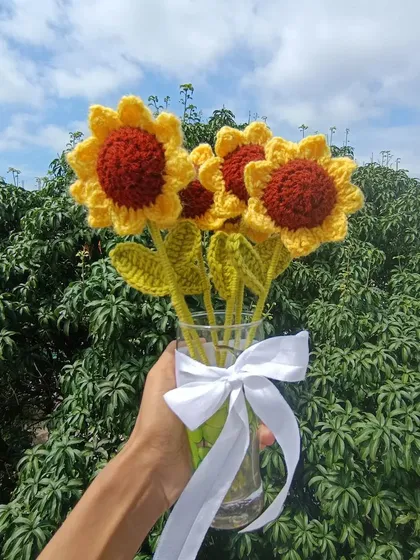 A bouquet of five sunflowers held up against the sky.