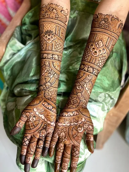 Full coverage bridal mehendi with delicate floral bands and traditional motifs extending up the arm.