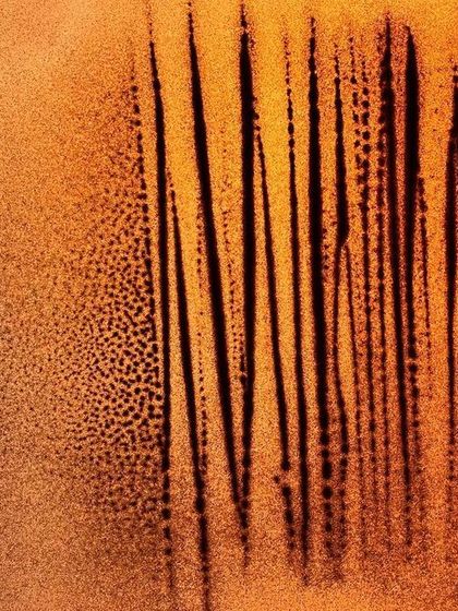 An untitled abstract work focusing on vertical lines and texture. The interplay between the fine, dotted sand and the stark black lines creates a sense of rhythm and depth.