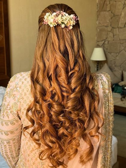 The full back view of the floral half-up style, showcasing the beautiful curls and fresh flower accessory.