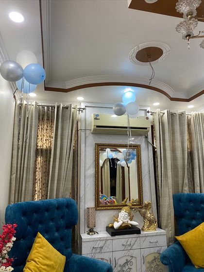 Simple and sweet home decoration for a baby's arrival, with bunches of blue, white, and silver balloons floating in the living room.