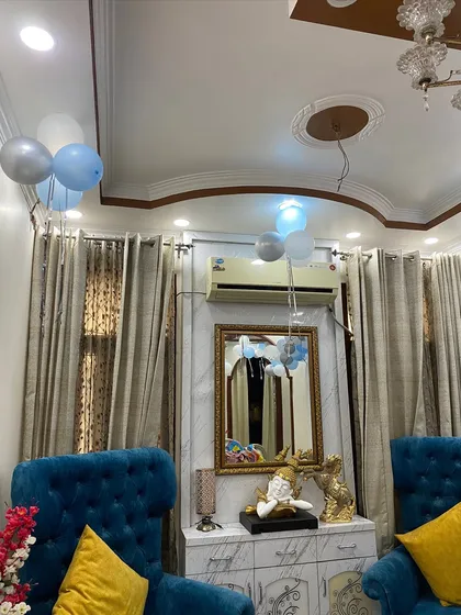 Simple and sweet home decoration for a baby's arrival, with bunches of blue, white, and silver balloons floating in the living room.