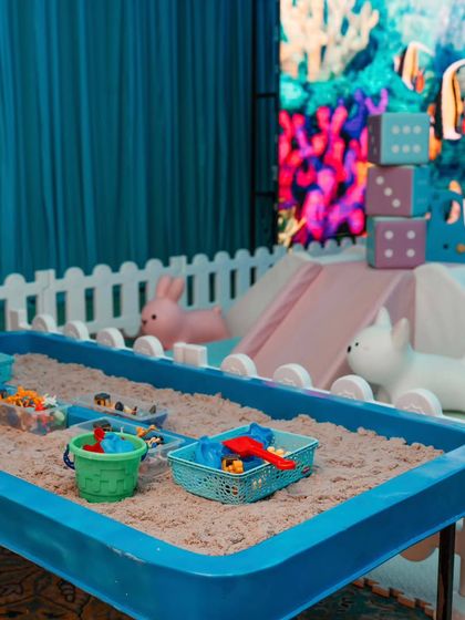 A sand play table adds another layer of sensory fun for the children. The backdrop of a vibrant digital coral reef keeps the activity tied to the 'Under the Sea' theme.