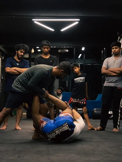 Students gather around to observe a live demonstration of a Jiu-Jitsu submission, learning through watching.