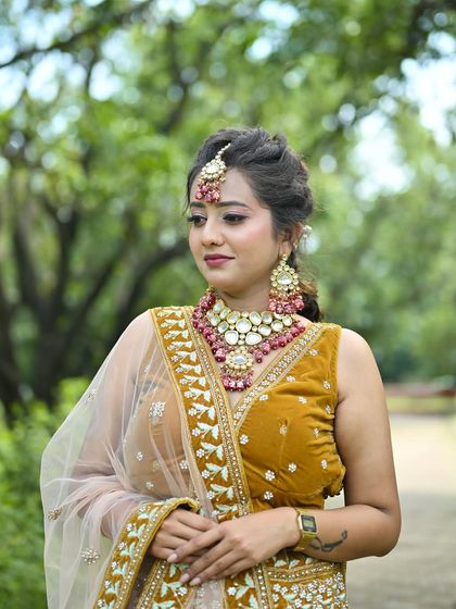 A three-quarter view of the mustard yellow lehenga, showing the intricate embroidery on the skirt and the matching pink-accented jewellery.