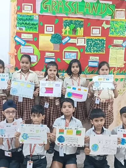 A group of students presents their Earth Day posters in the classroom. These activities provide a platform for students to visually communicate their ideas on sustainability and conservation.