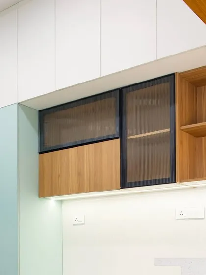 A detail shot of the upper cabinets, where I've mixed solid sage green, natural wood, and fluted glass to create visual interest and texture.