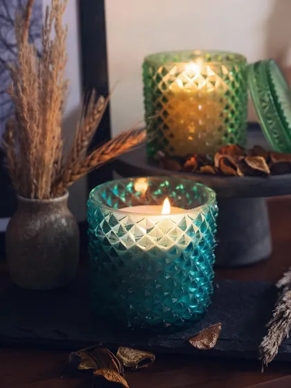 Two of our diamond-cut jar candles, one in a vibrant teal and the other in green. The textured glass and rich colors make these candles a beautiful decorative accent for any shelf or table.