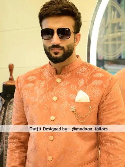A close-up of the peach Jodhpuri blazer, highlighting the delicate embroidery and the stylish pocket square with a chain accessory.