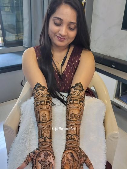 A happy bride admiring her freshly done mehndi. This design includes portraits and various traditional symbols, customized to her wishes for her special day.