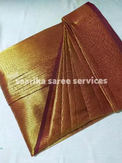 A shimmering gold and maroon saree, folded to perfection.