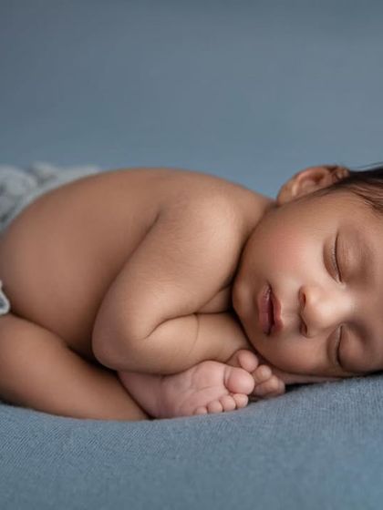 The 'taco' pose on a blue background, a perfect way to show how tiny and curled up newborns are.