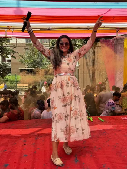 A triumphant pose on the stage at a Holi party, covered in colors but full of energy.