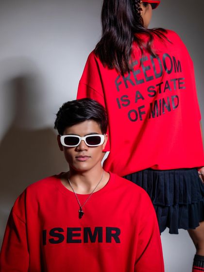 A dual-model shot showcasing oversized sweatshirts. The composition cleverly shows both the front graphic on the male model and the back graphic on the female model in a single frame.
