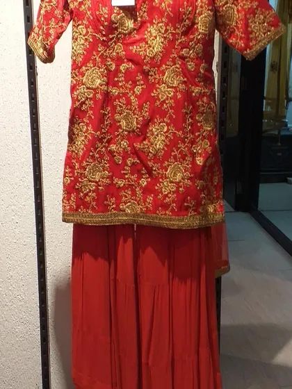 A classic red sharara suit with heavy gold embroidery on the short kurta. This traditional and vibrant outfit is perfect for celebrating festivals or attending a wedding.