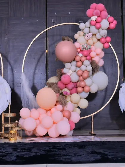 Detail of the organic balloon garland on a golden hoop, featuring a mix of matte and chrome balloons with pampas grass accents.