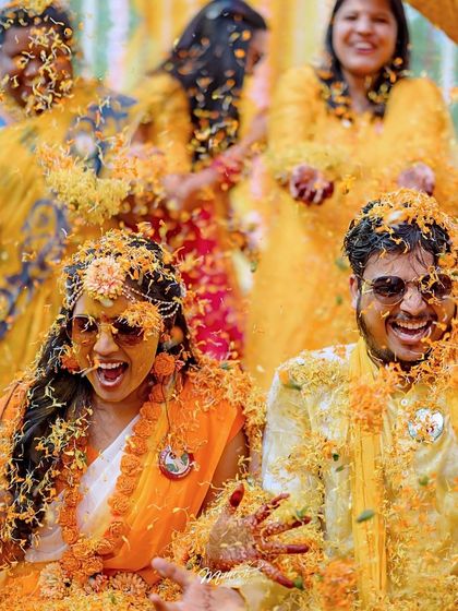 An explosion of marigold petals! This action shot captures the peak excitement and vibrant colors of the Haldi.
