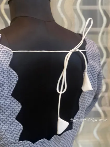 A simple yet chic back design with a scalloped edge and a delicate tie-up with tassels, perfect for a minimalist look.