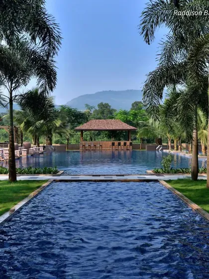 The serene pool at Radisson Blu, Karjat, framed by palm trees. This resort is a perfect weekend getaway destination from Mumbai for a wedding.