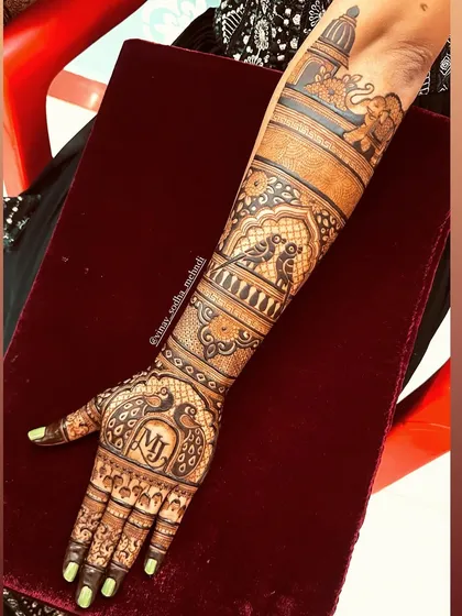This back-hand design features personalized initials 'MJ' and is filled with traditional motifs like peacocks and elephants.