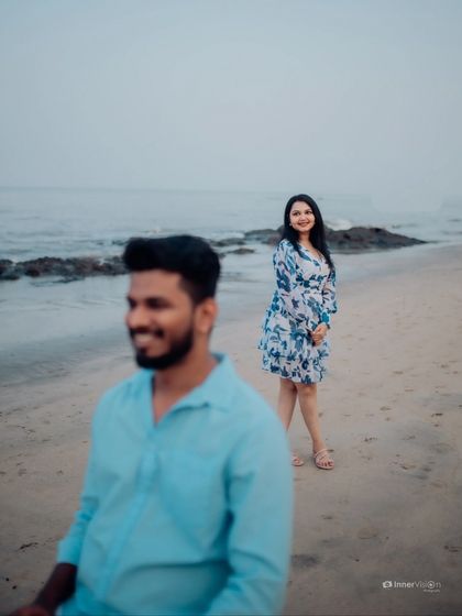 An artistic shot using depth of field to create a story. The focus is on the bride in the background, watching her partner with a smile, creating a sense of anticipation and love.