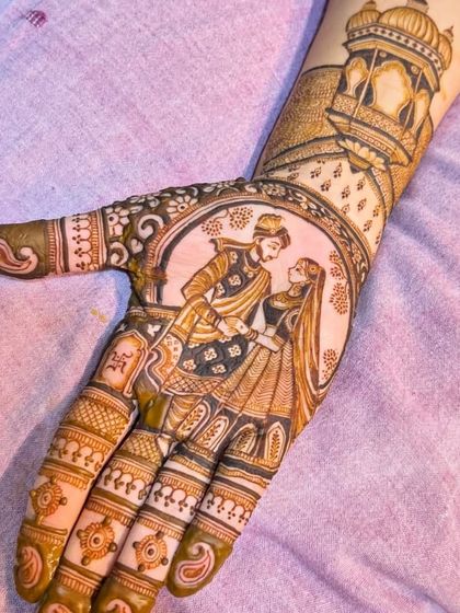 A close-up of a beautifully executed couple portrait on the palm. The groom is lovingly looking at the bride, with a royal jharokha design on the wrist.