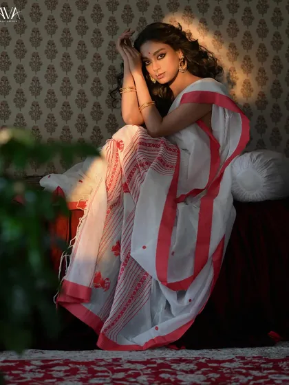 A full-length shot using light and shadow to create a dramatic effect. The sunlight streaming in from the side highlights the model and the texture of her handloom saree.
