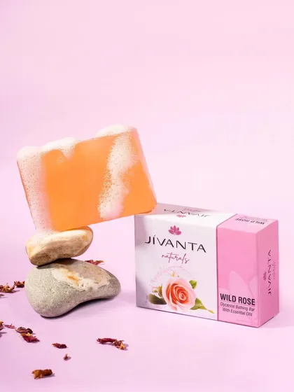 A creative shot of Jivanta Naturals' Wild Rose soap, balanced on stones to create a sense of natural harmony. The soap lather texture is visible, highlighting its cleansing properties.