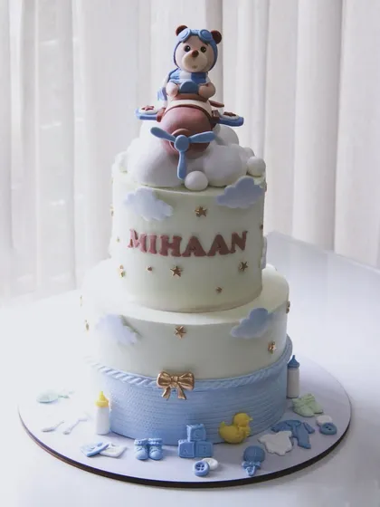 A full view of the welcome baby cake for Mihaan, showing the airplane theme on the top tier and sweet baby details on the bottom.