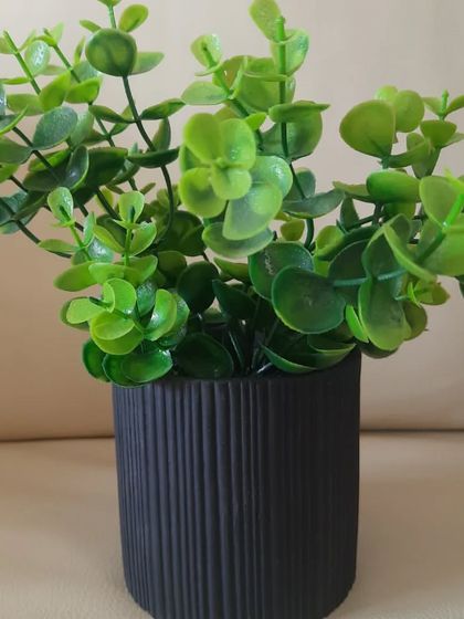 This black ribbed planter is styled with artificial eucalyptus stems. The combination of the dark pot and the soft green of the leaves creates a very calming and contemporary look.