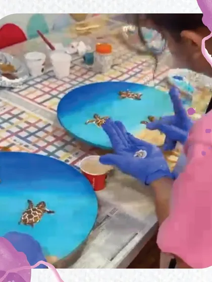 An overhead view of our resin art workshop in progress. Students are carefully placing their turtle figures into the blue "ocean" they've created.