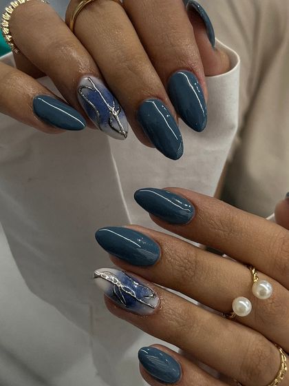 A sophisticated combination of solid teal and a hand-painted marble accent nail with a silver leaf detail. This shows how an accent nail can elevate a whole set.