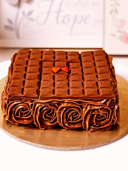 This beautiful square chocolate cake is a work of art. Topped with chocolate bars and surrounded by delicate chocolate rosettes, it's perfect for any celebration.