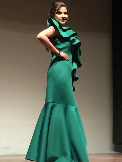 Make a statement in this emerald green mermaid gown with dramatic one-shoulder ruffle detail. This evening gown rental is ideal for formal events, award functions, or a glamorous cocktail night.