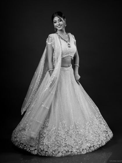 A smiling, full-length monochrome portrait in a beautiful lehenga. This black and white version offers a timeless, classic alternative to the color bridal shot.