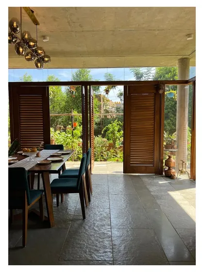 The dining room of "Villa 34" is designed as a glass pavilion that sits within the garden. Louvered wooden shutters can be opened or closed to control light and privacy.