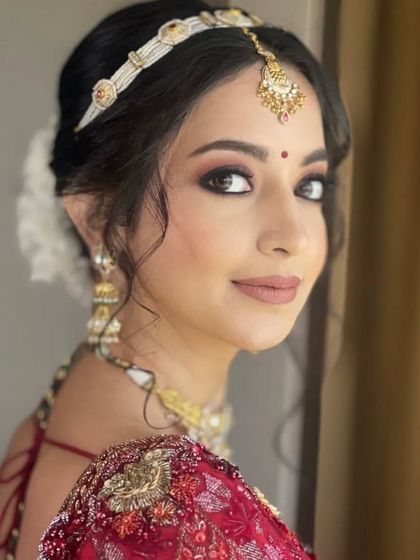 This bride is ready for her phera ceremony with a classic low bun adorned with beautiful white flowers. The matha patti headband completes this traditional and graceful look.