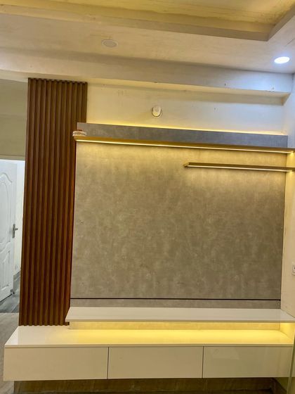 A floating TV cabinet with a textured grey back panel and wood-fluted side detailing, illuminated by warm LED strip lights.