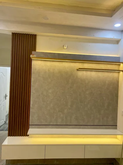 A floating TV cabinet with a textured grey back panel and wood-fluted side detailing, illuminated by warm LED strip lights.