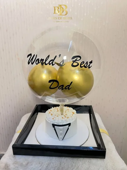 A sophisticated Father's Day gift featuring a tuxedo-themed bento cake and a "World's Best Dad" balloon display.