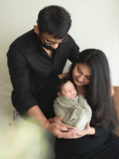 A family united in their love for their new baby. The coordinated black outfits create a striking contrast, making the moment feel both modern and timeless.